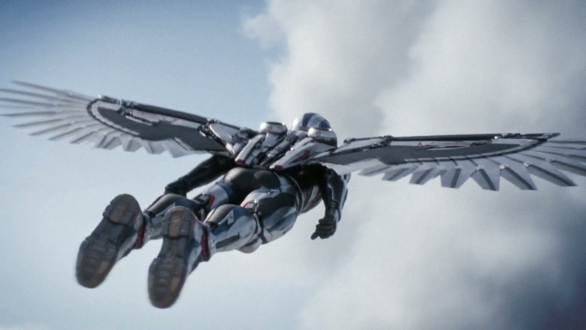 A winged mechanical figure in flight against open sky and cloud